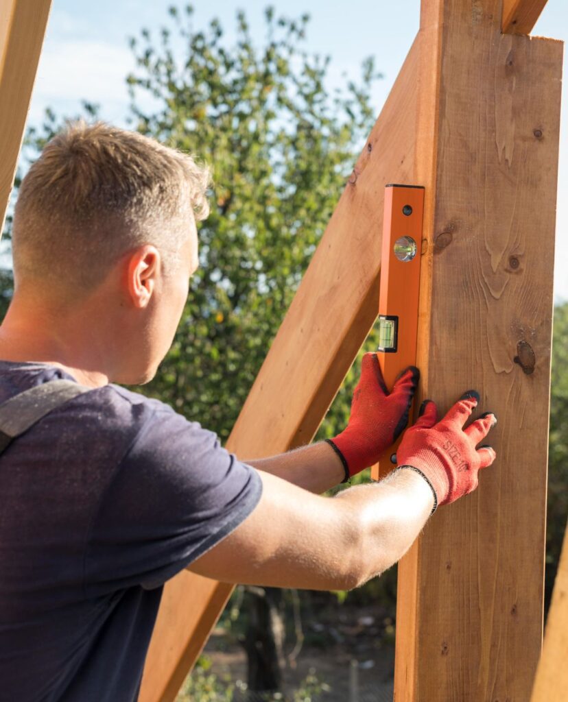 Carpenter man taking measures on a wood plank