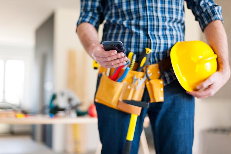 A close up image of a fence construction worker with a mobile phone