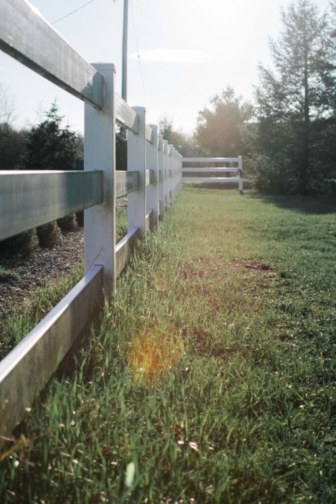 a shot of a gray wooden fence on the grass field during daytime